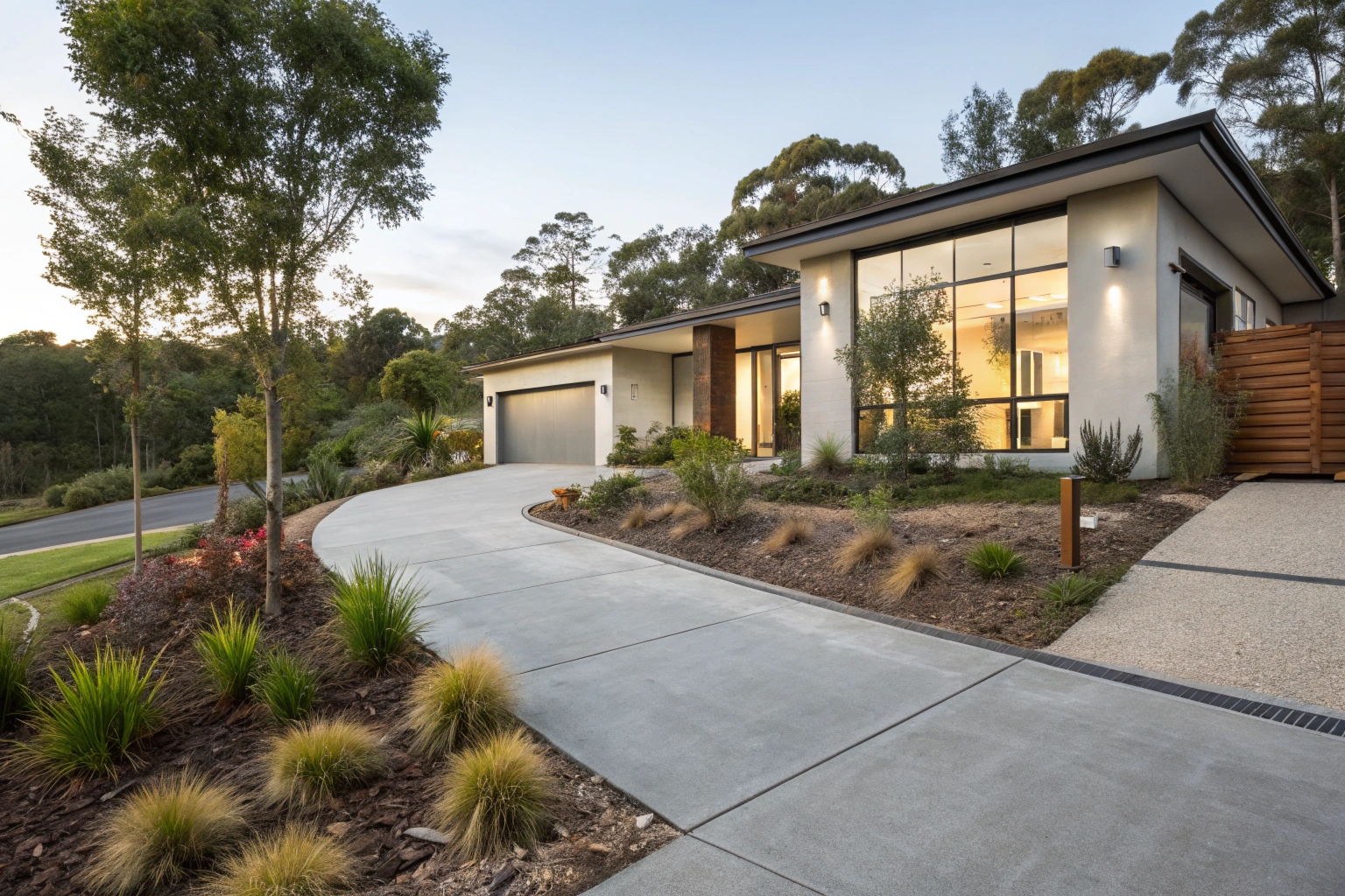 Front view of modern Australian home with decorative concrete driveway, contemporary facade, native garden landscaping
